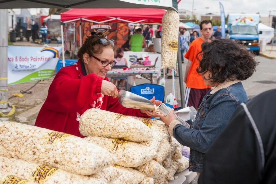 A woman is selling popcorn to another woman at a market.