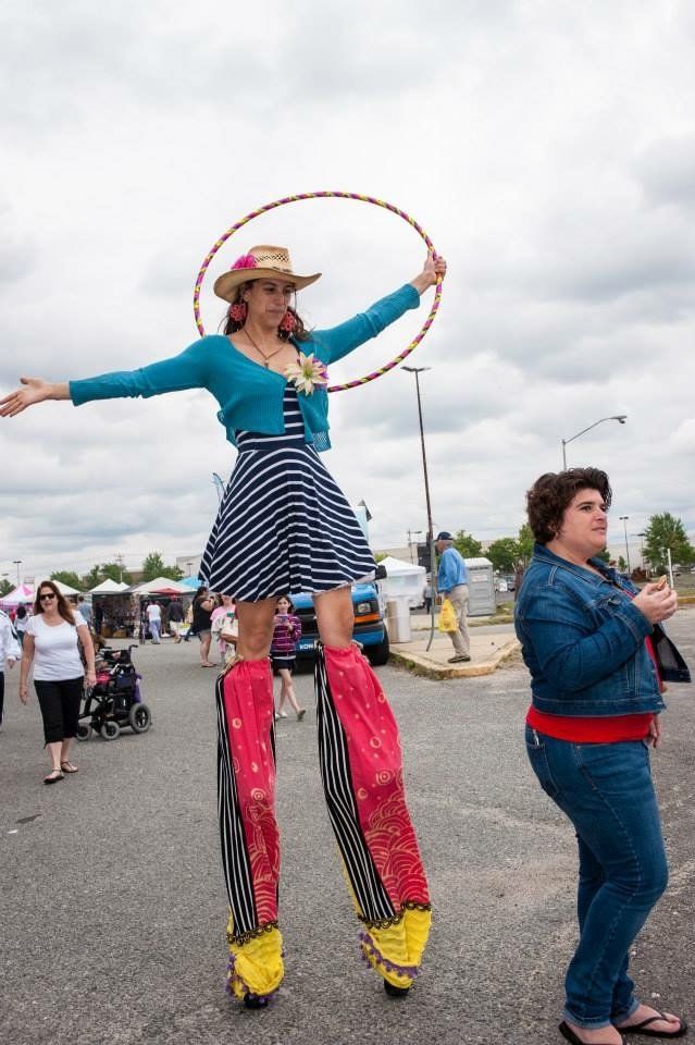A woman is standing on stilts holding a hula hoop.