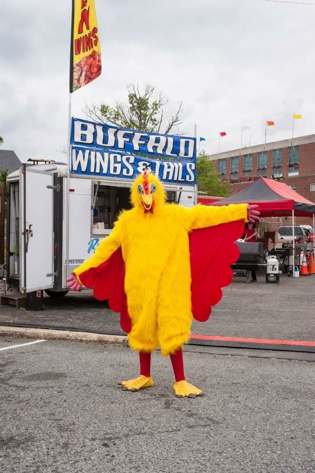 A man in a chicken costume is standing in front of a buffalo wings truck.