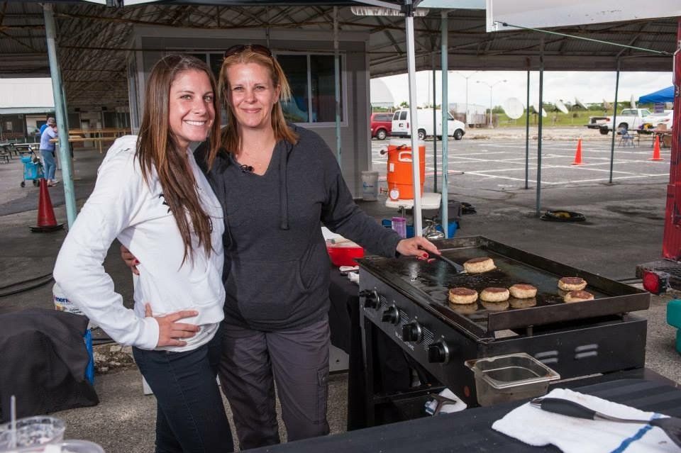 Two women standing next to each other in front of a grill