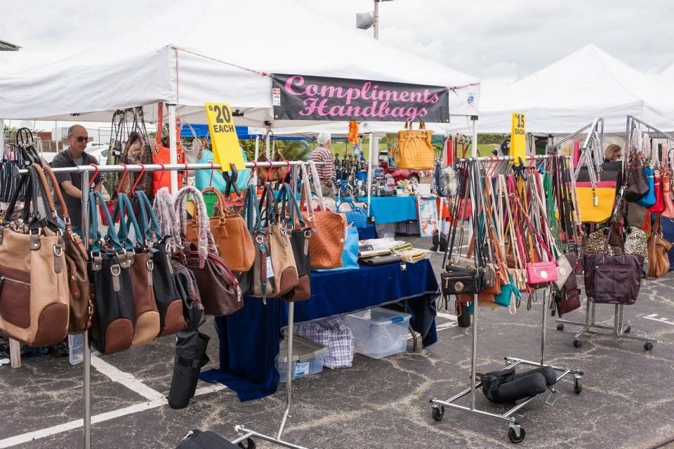 A lot of handbags are on display at a flea market