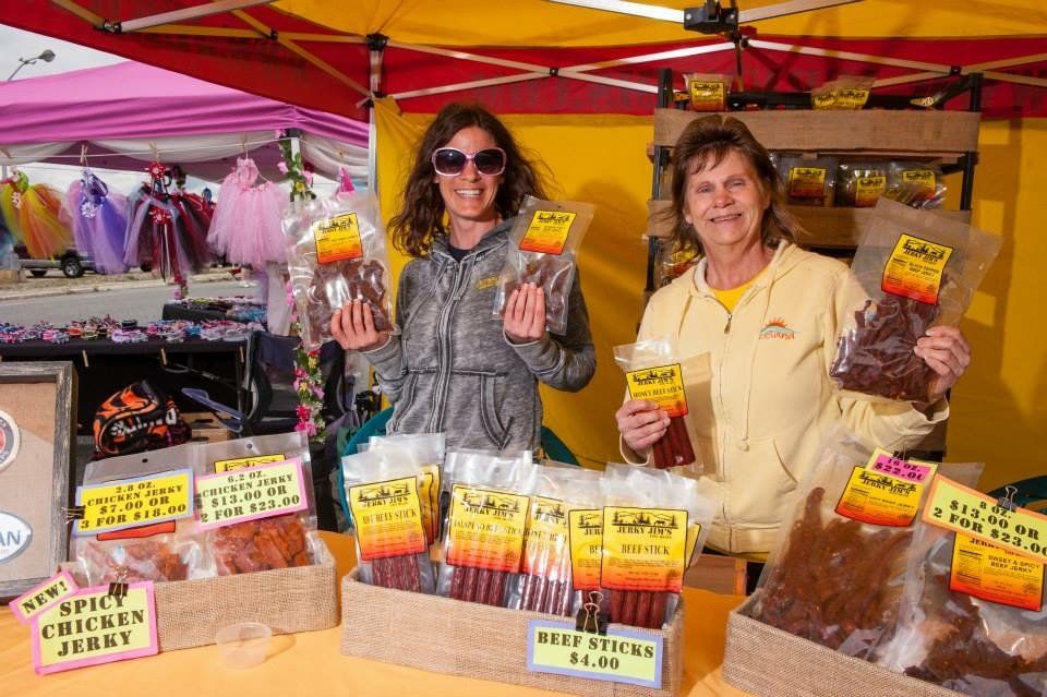 Two women are selling beef jerky at a market
