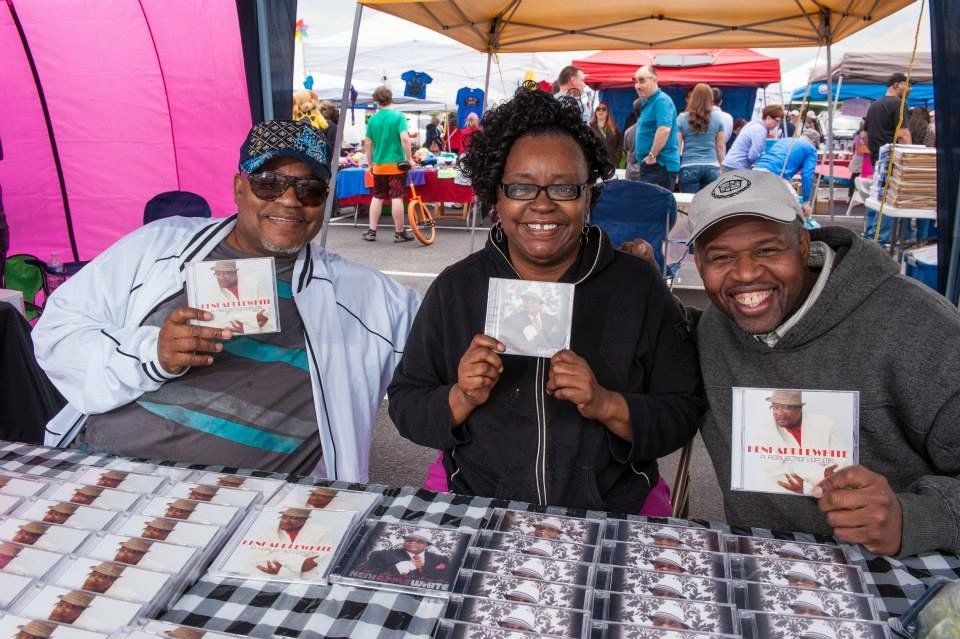 Three people are sitting at a table holding cds.