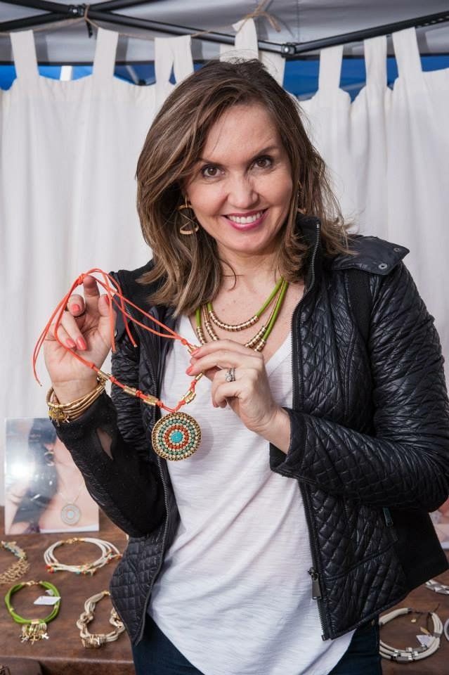 A woman in a black jacket is holding a necklace in her hands.
