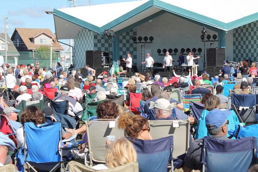 A crowd of people sitting in chairs watching a band on stage