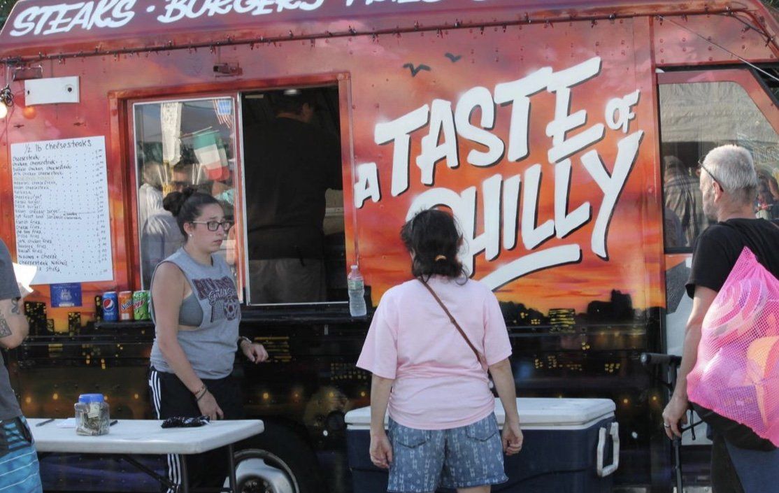 People standing in front of a food truck that says a taste of chilly