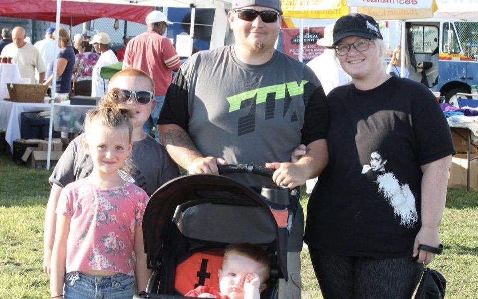 A family posing for a picture with a man wearing a t-shirt that says ttx