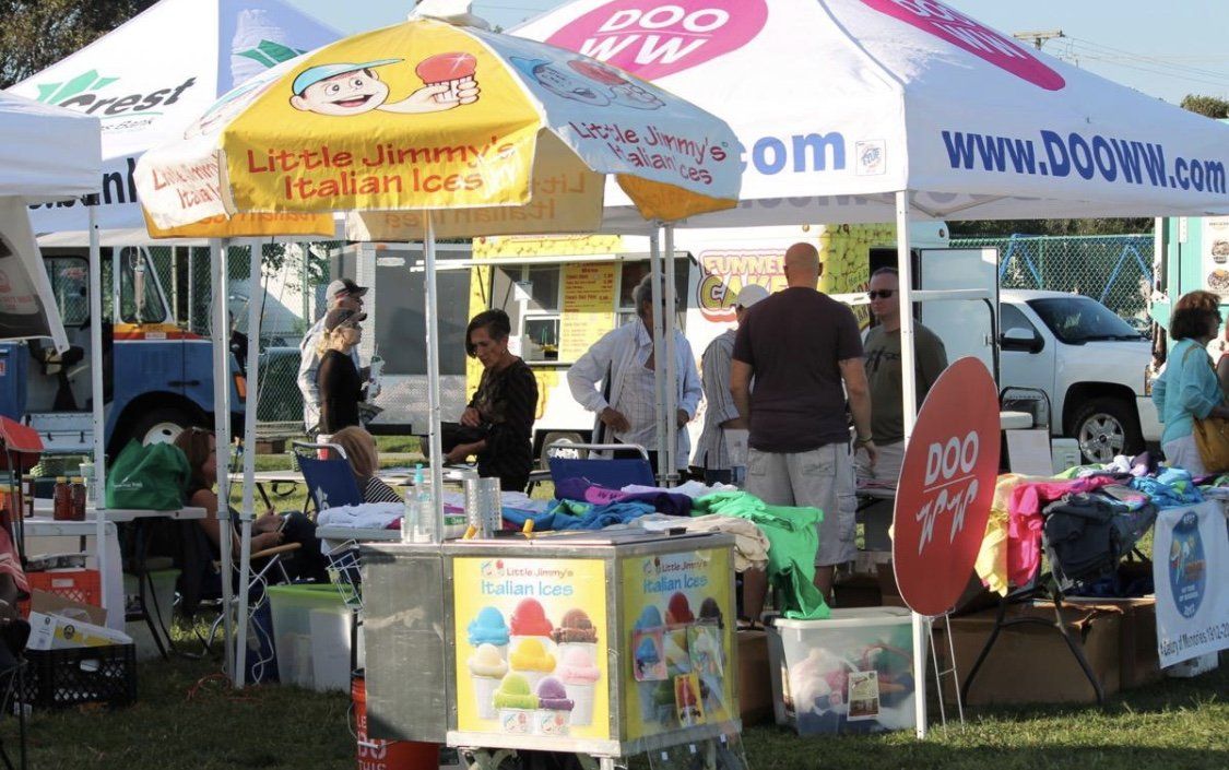 A group of people are gathered under umbrellas including one that says little liberty