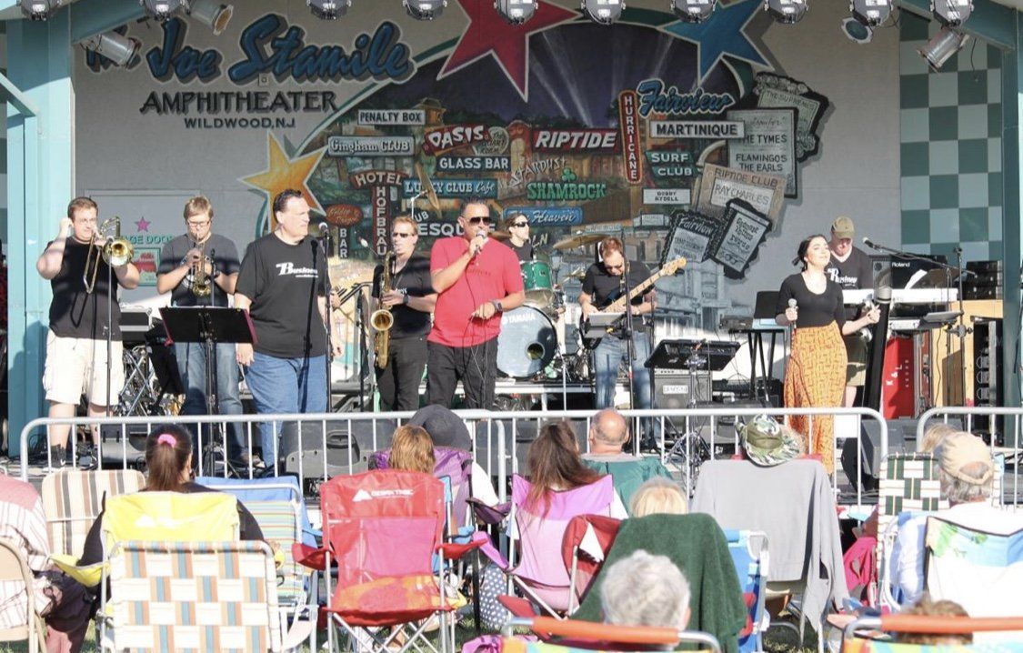 A group of people are sitting in chairs watching a band perform on a stage.