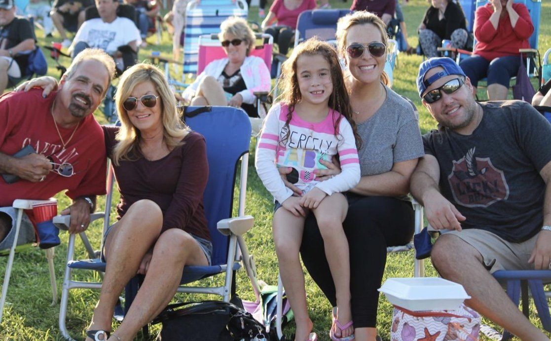 A group of people are posing for a picture while sitting in chairs in the grass.