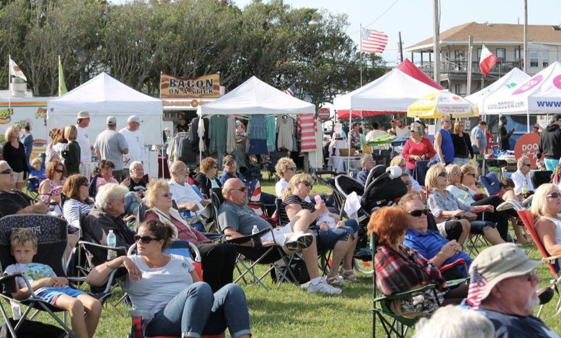 A large group of people are sitting in chairs at a festival.
