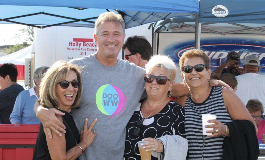 A group of people posing for a picture with a man wearing a shirt that says doo ww