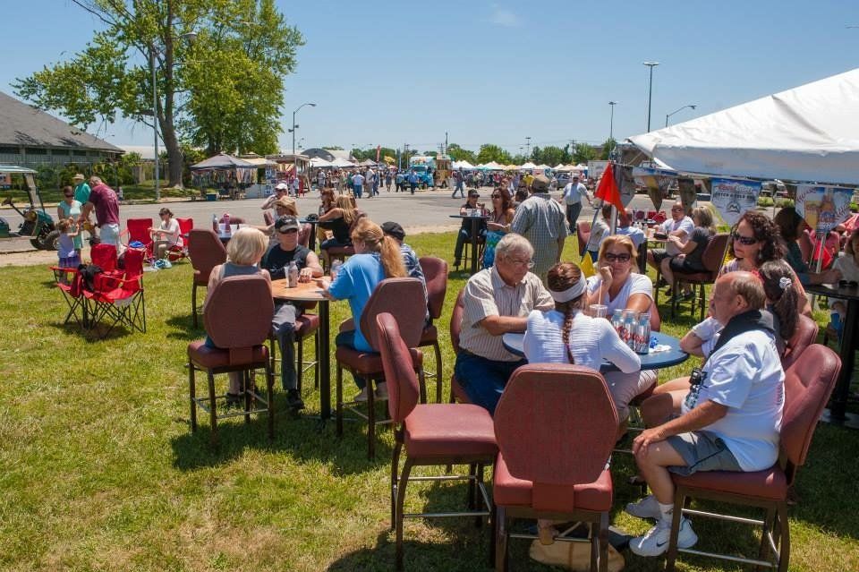 A group of people are sitting at tables in a park.