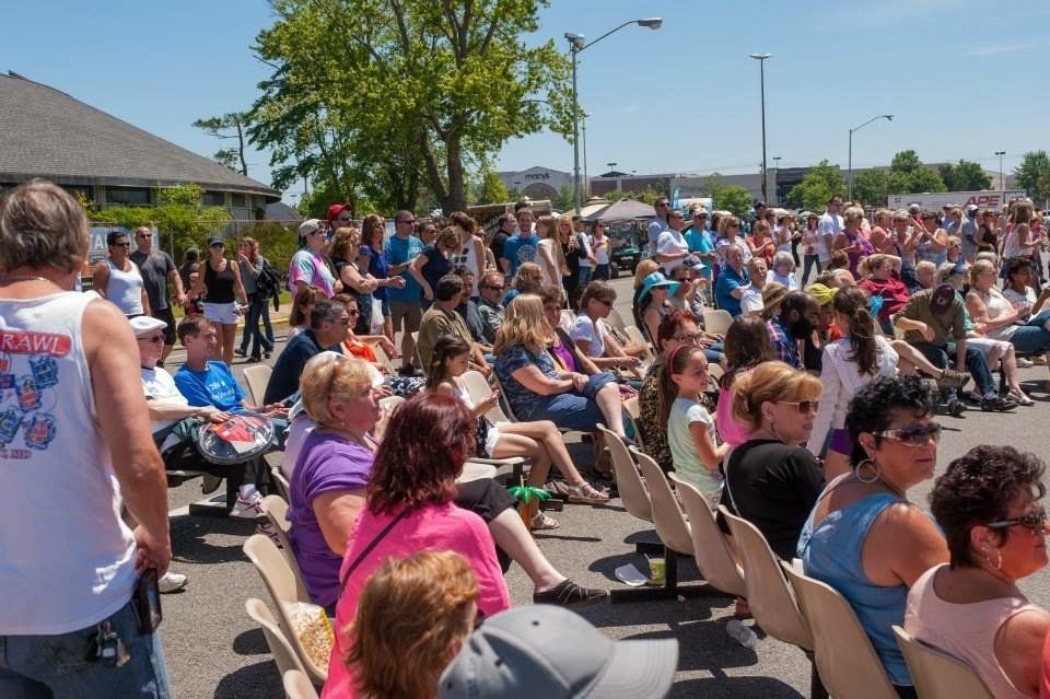 A large group of people are sitting in chairs outside on a sunny day.