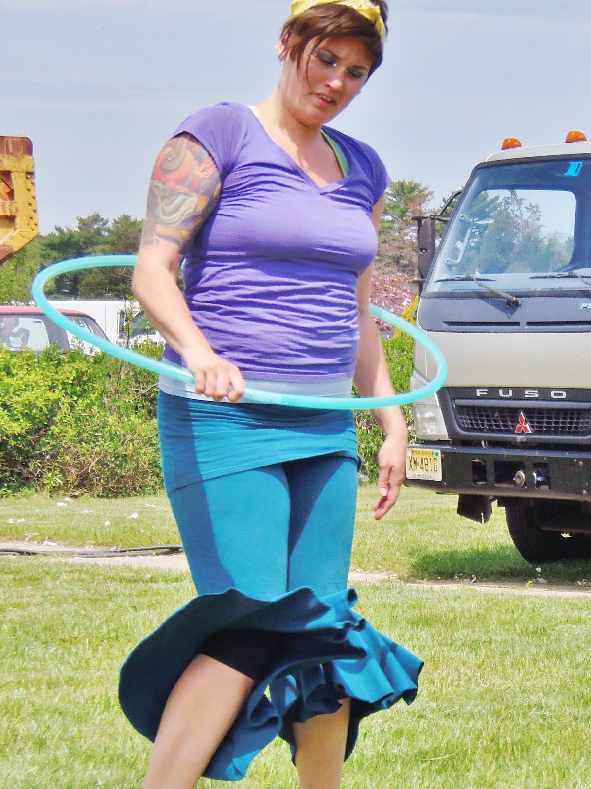 A woman playing with a hula hoop in front of a mitsubishi truck