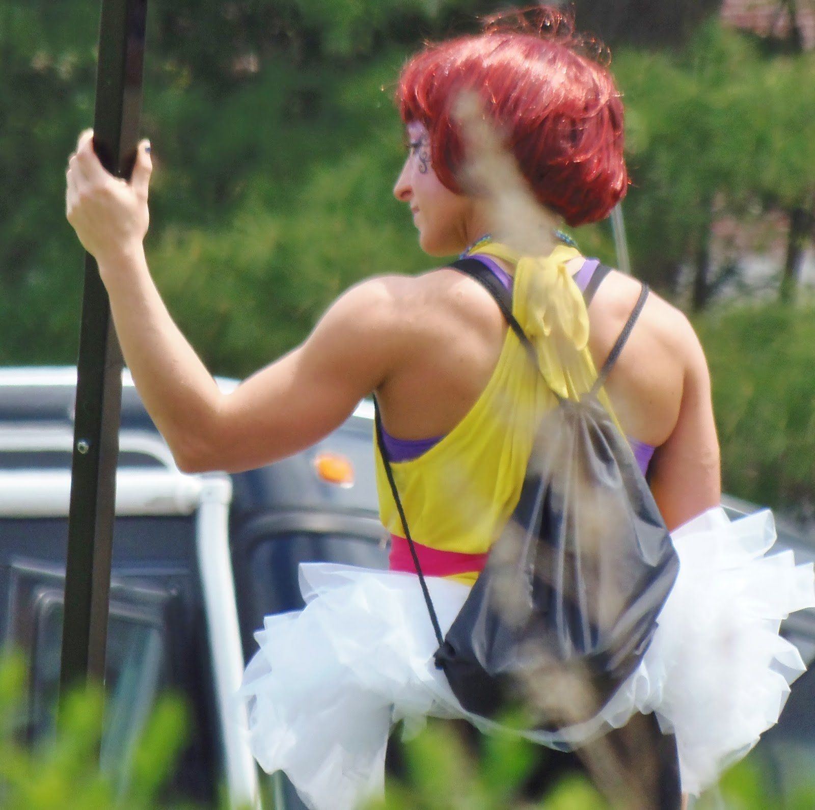 A woman with red hair is wearing a yellow tank top