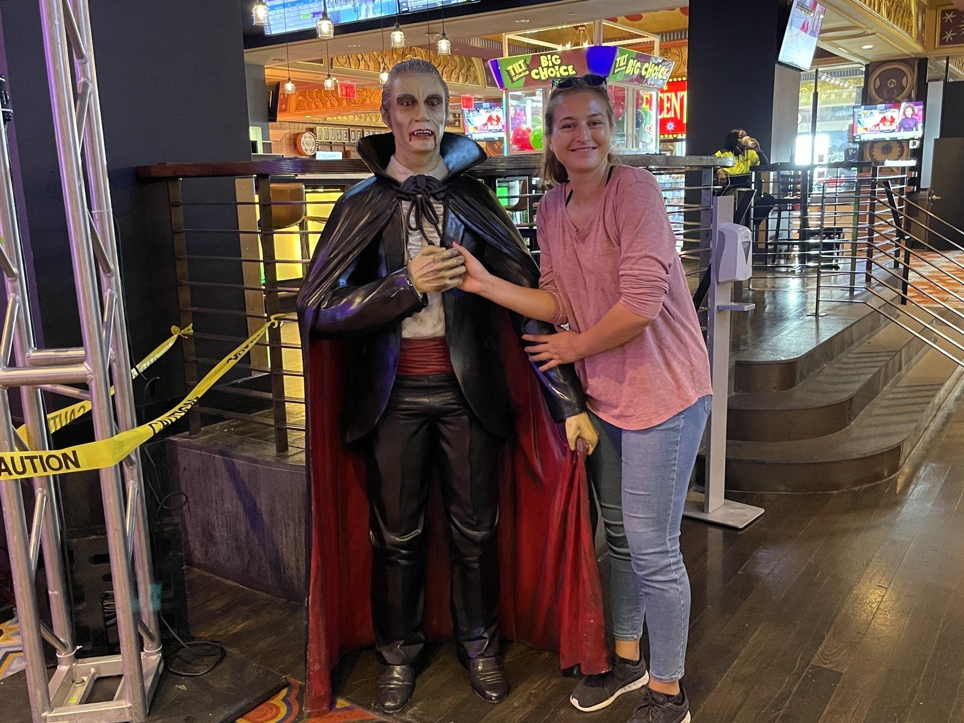 A woman is standing next to a statue of a vampire.
