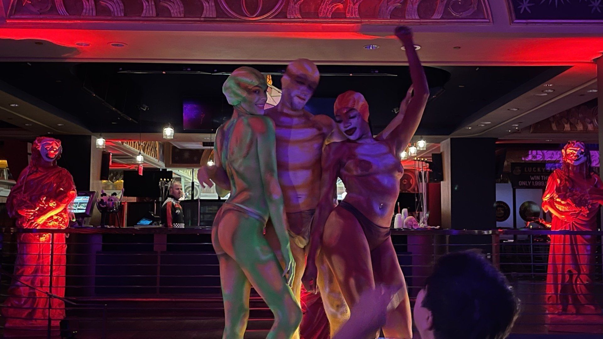 A group of people painted in different colors are dancing on a stage.