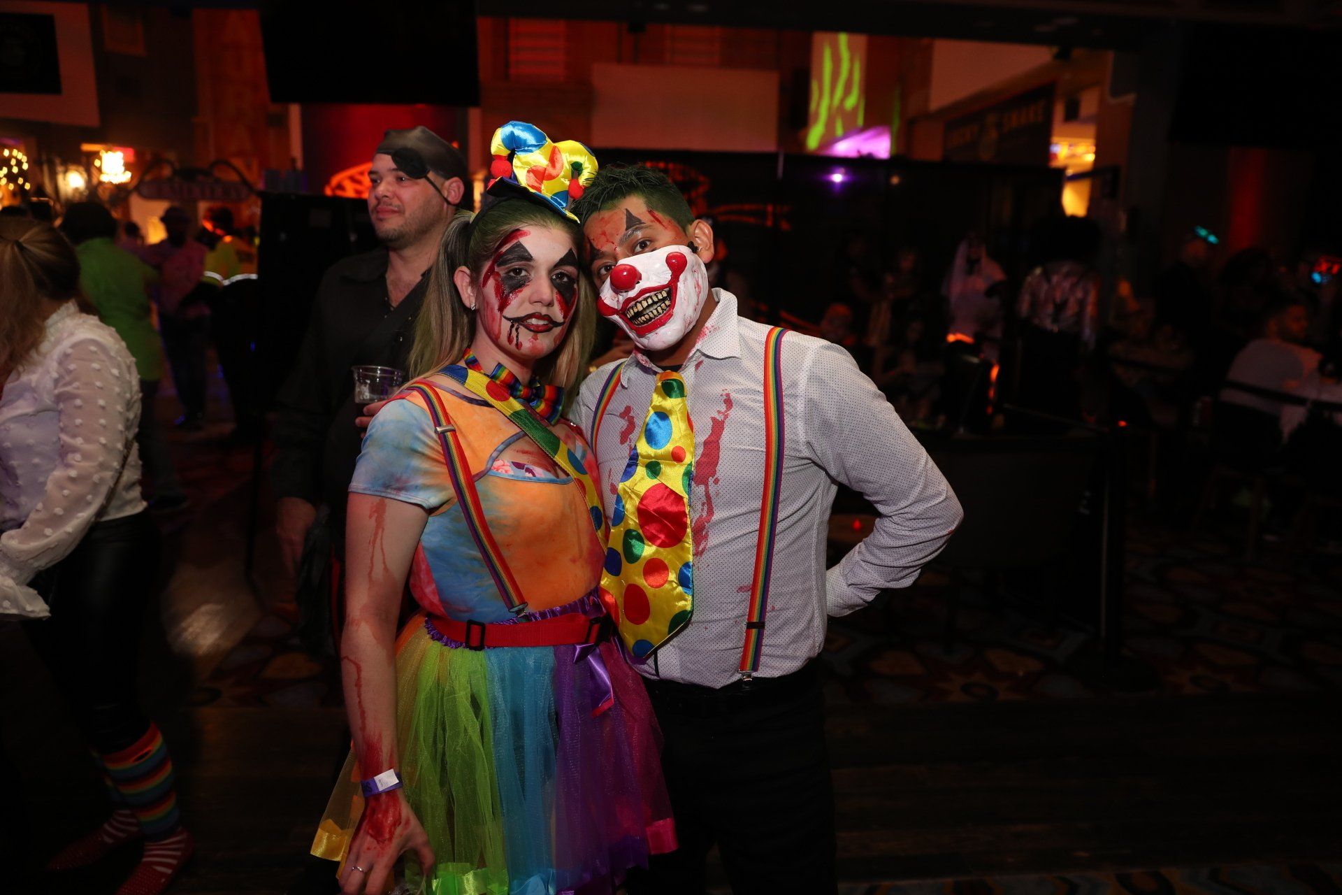 A man and a woman dressed as clowns are posing for a picture.