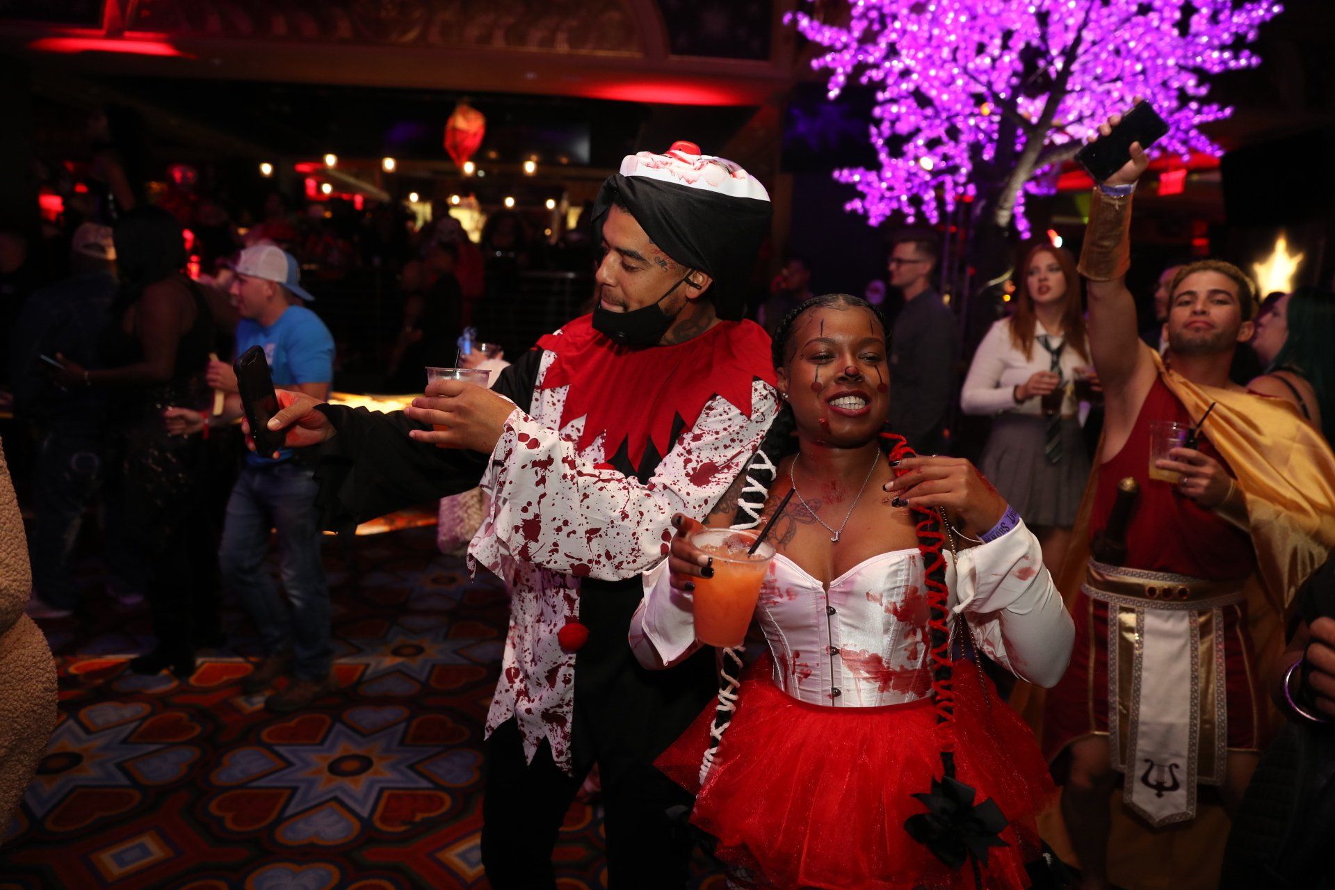 A man and a woman in halloween costumes are dancing at a party.