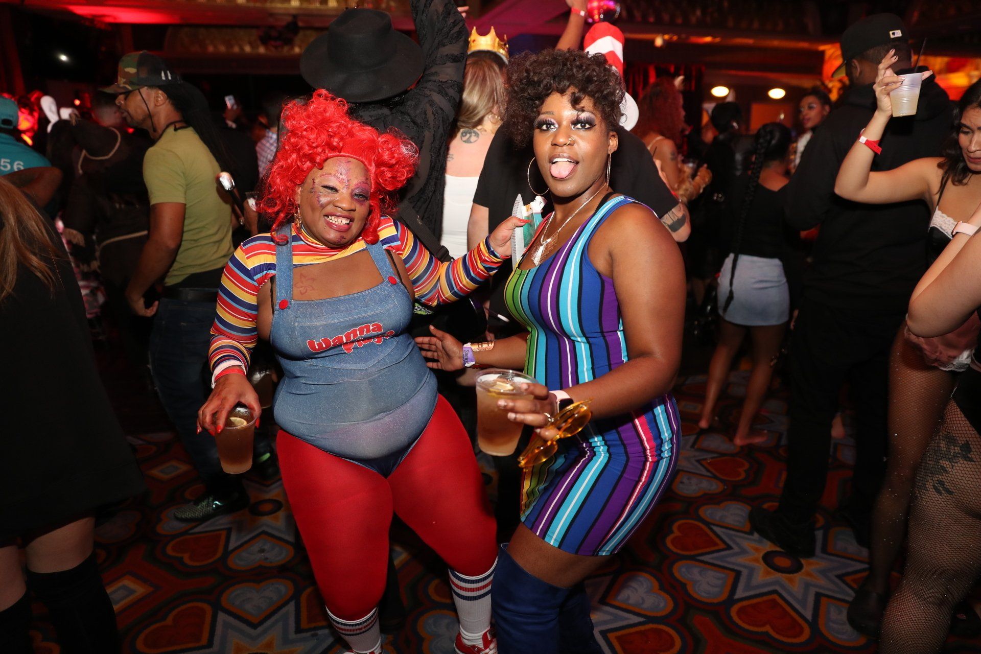 Two women in costumes are dancing in a crowded room