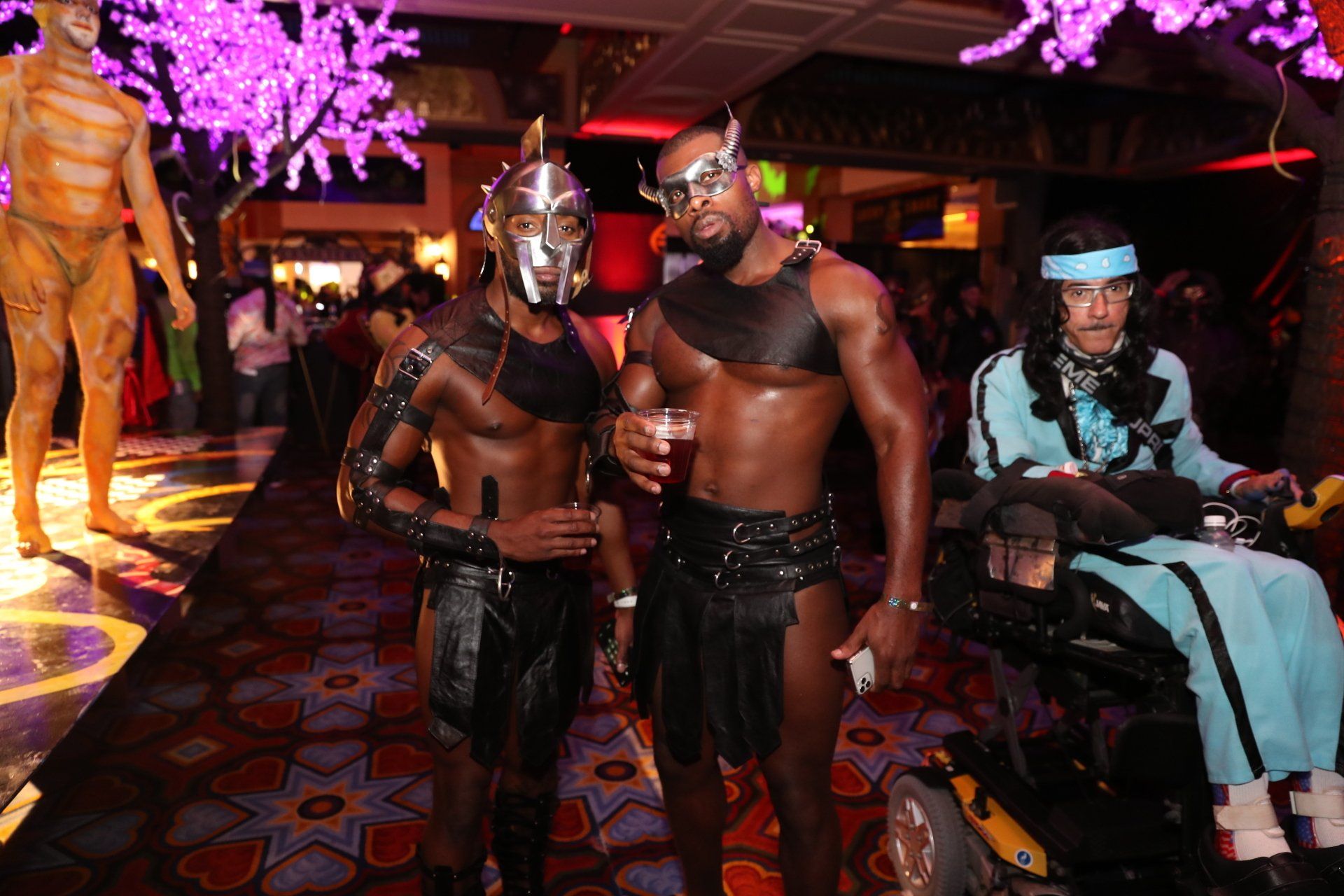 A man in a wheelchair is standing next to two men in costumes