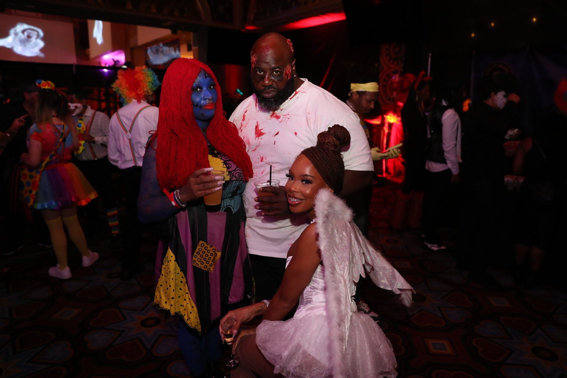 A group of people dressed in costumes are posing for a picture at a halloween party.