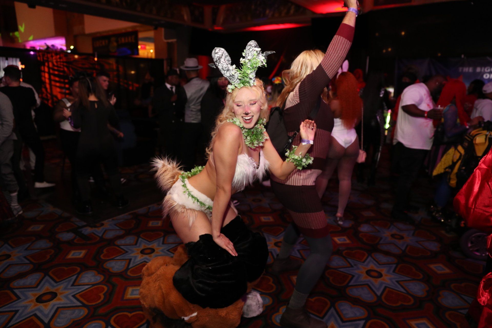 A woman in a bunny costume is sitting on a man 's lap at a party.