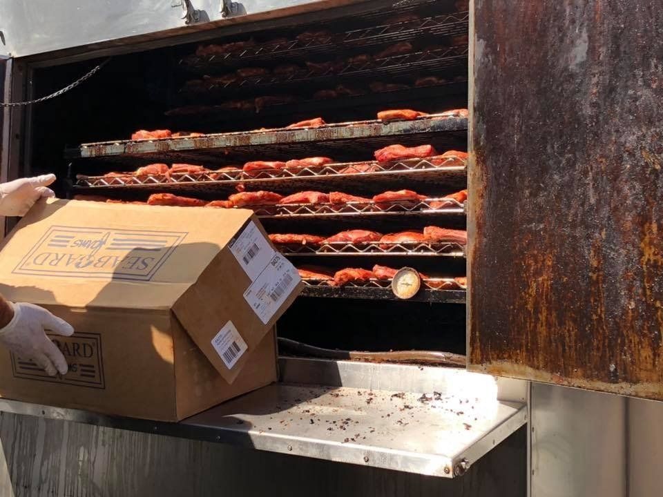 A person is putting a box into a smokehouse