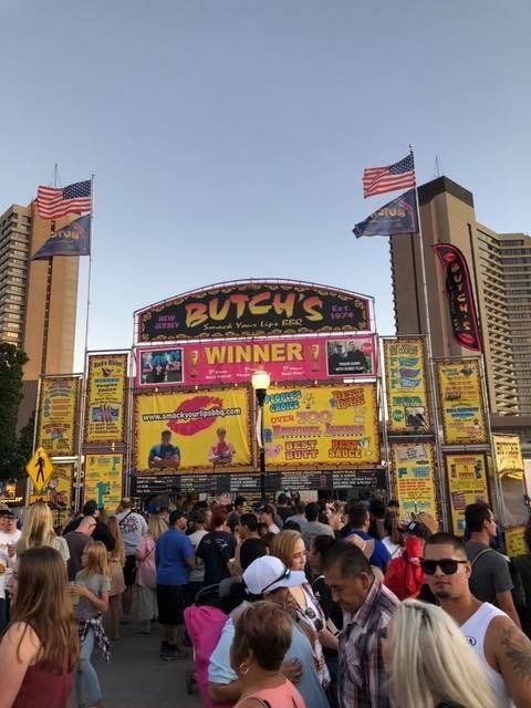 A crowd of people are gathered in front of a butch 's sign