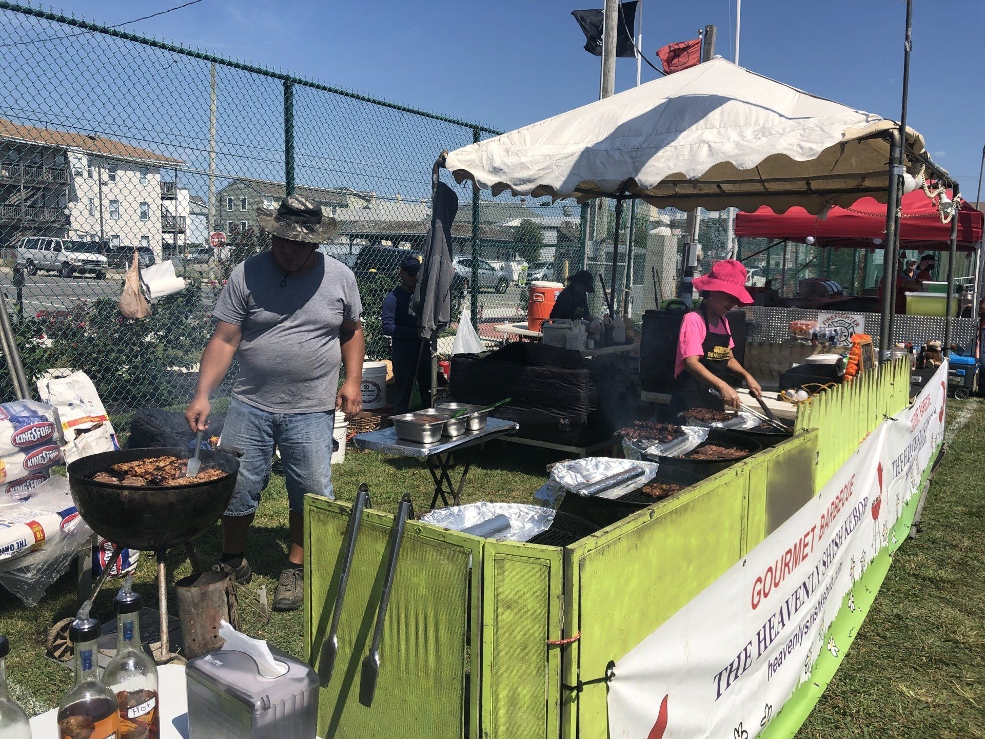 A man is cooking food on a grill in a field.