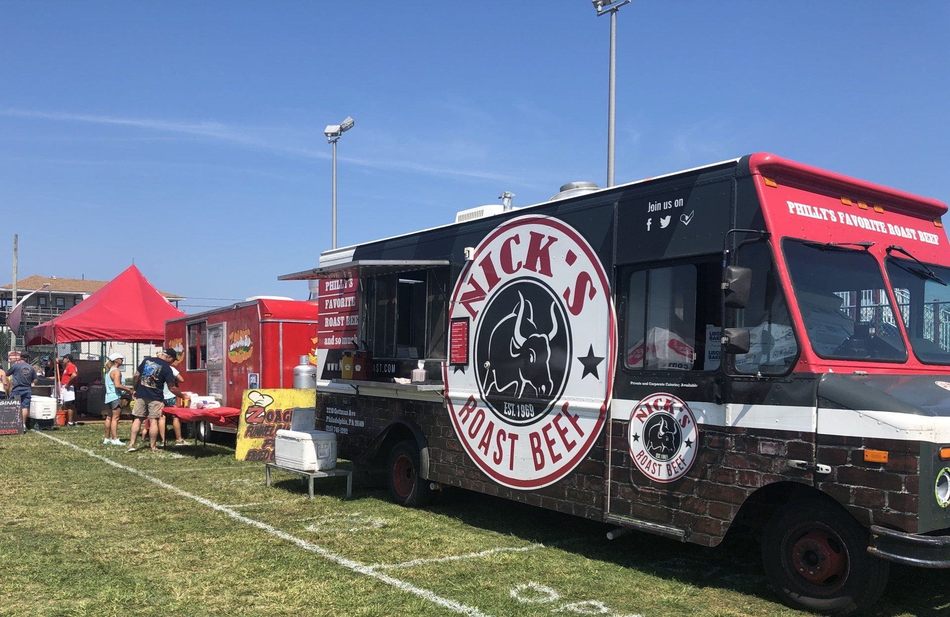 A food truck is parked in a grassy field.