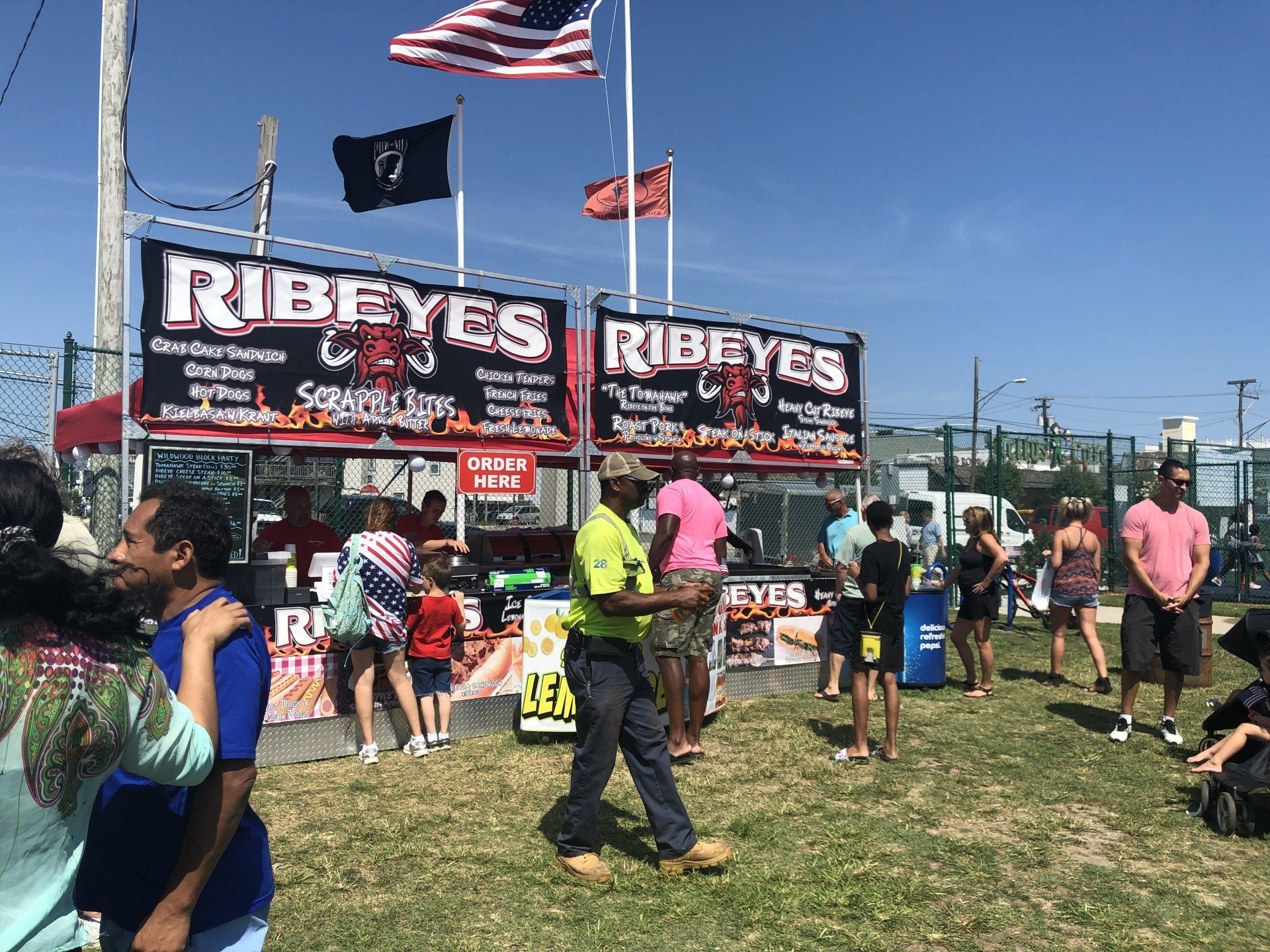 A group of people are standing in front of a food stand.