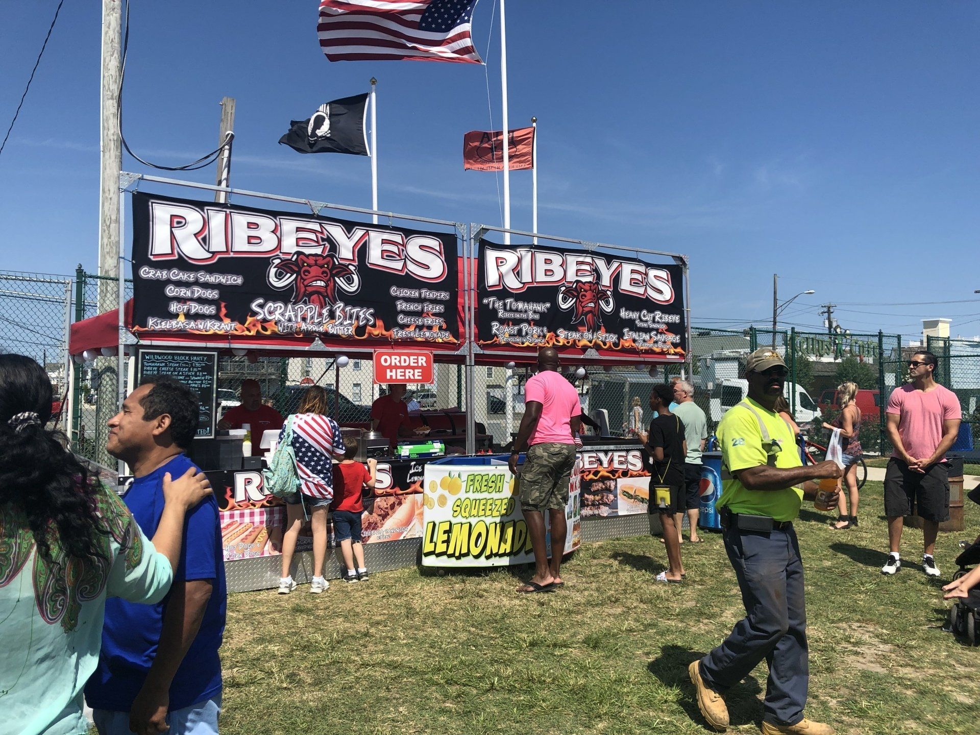 A group of people are standing in front of a food stand.
