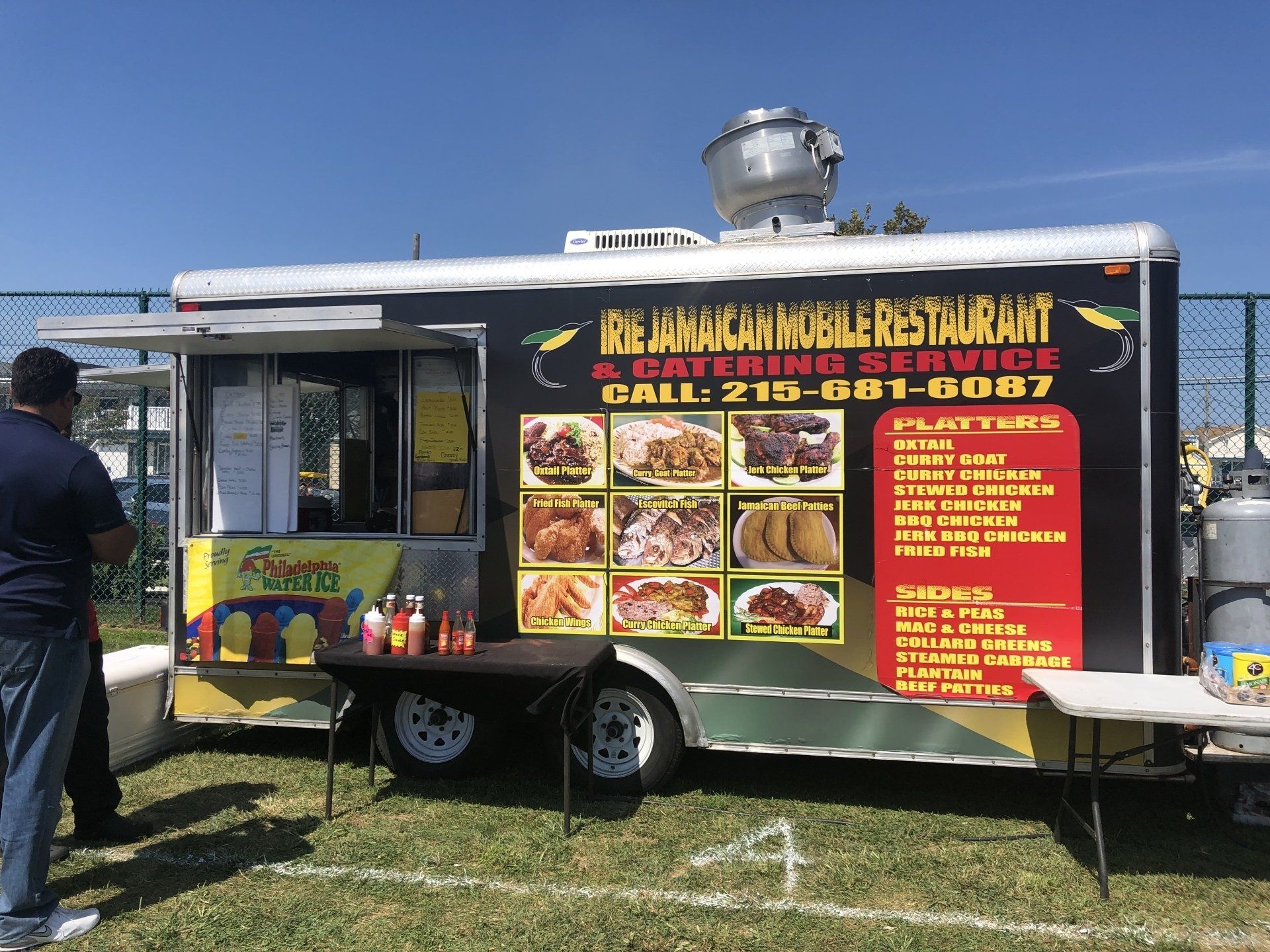 A man is standing in front of a food truck.