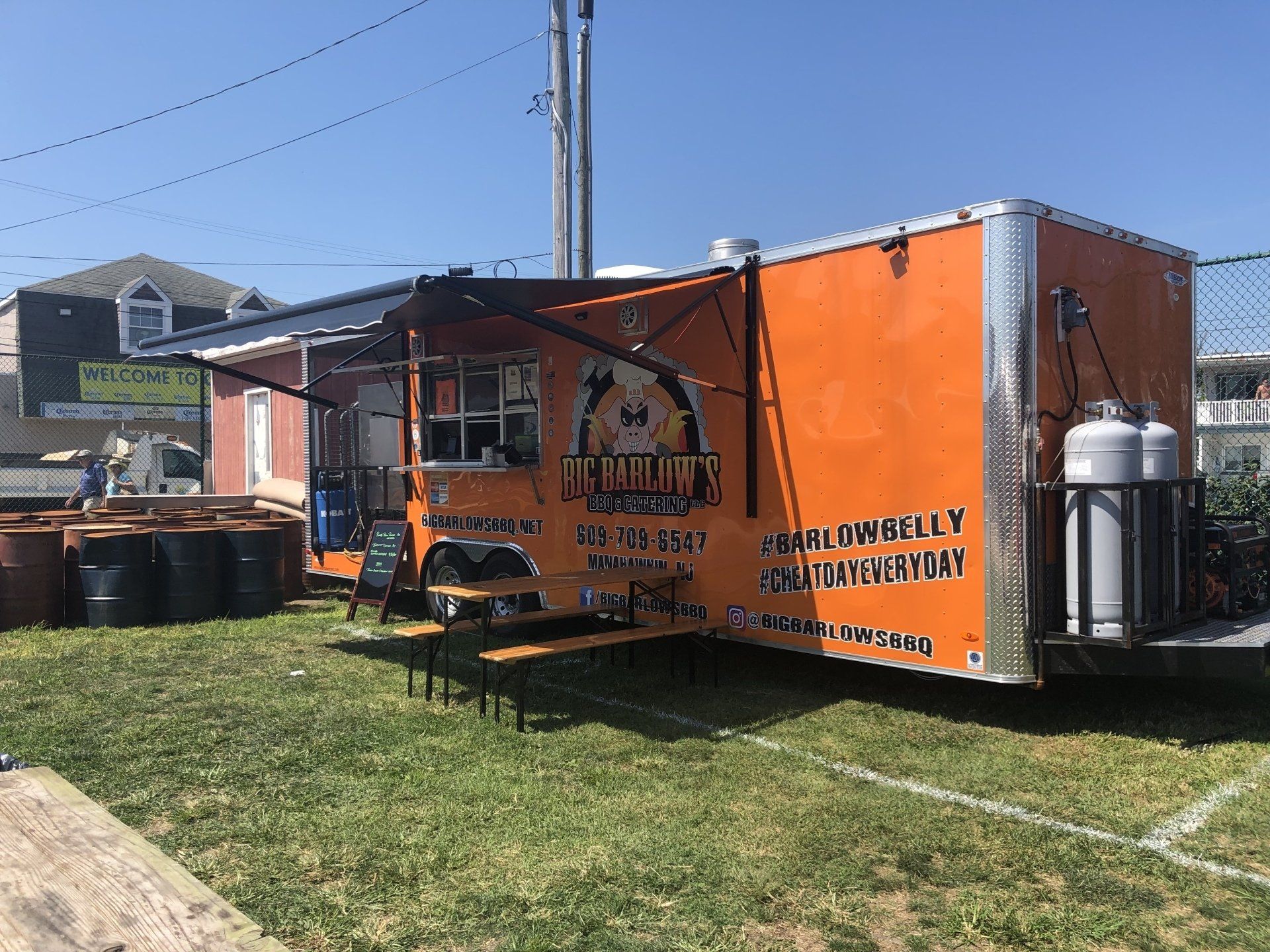 A food truck is parked in a grassy field.