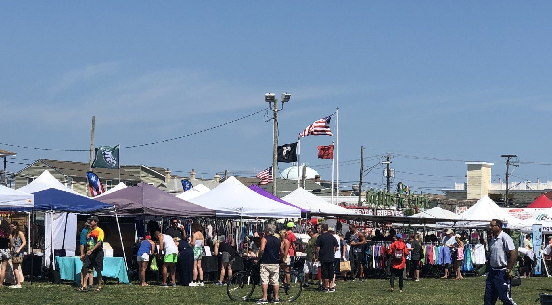 A crowd of people are gathered in a field with tents and flags.