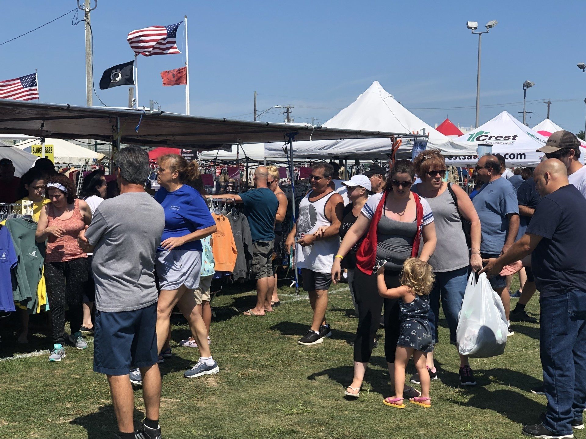 A group of people are standing in a field at a market.