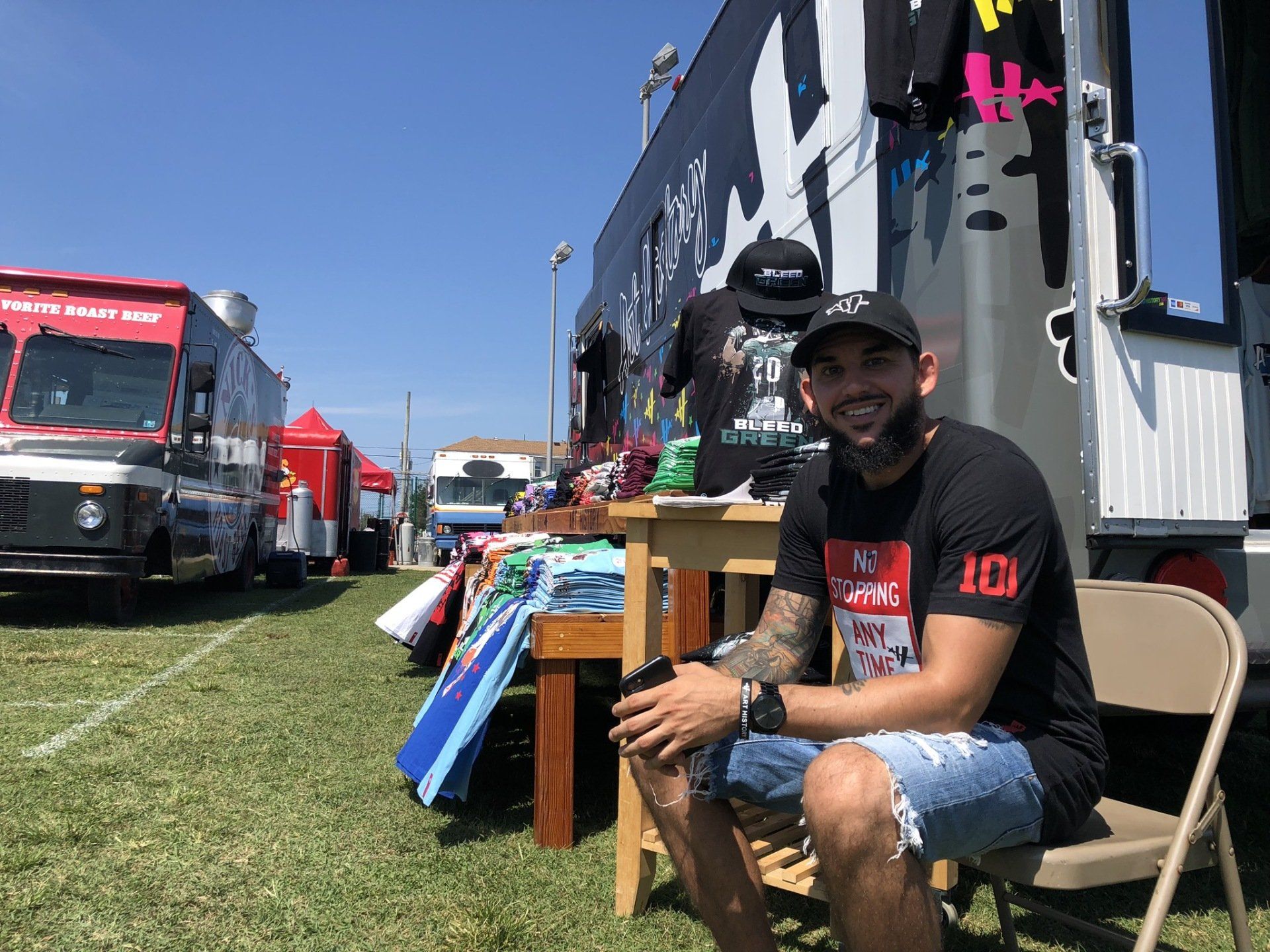 A man is sitting in a chair in front of a food truck.