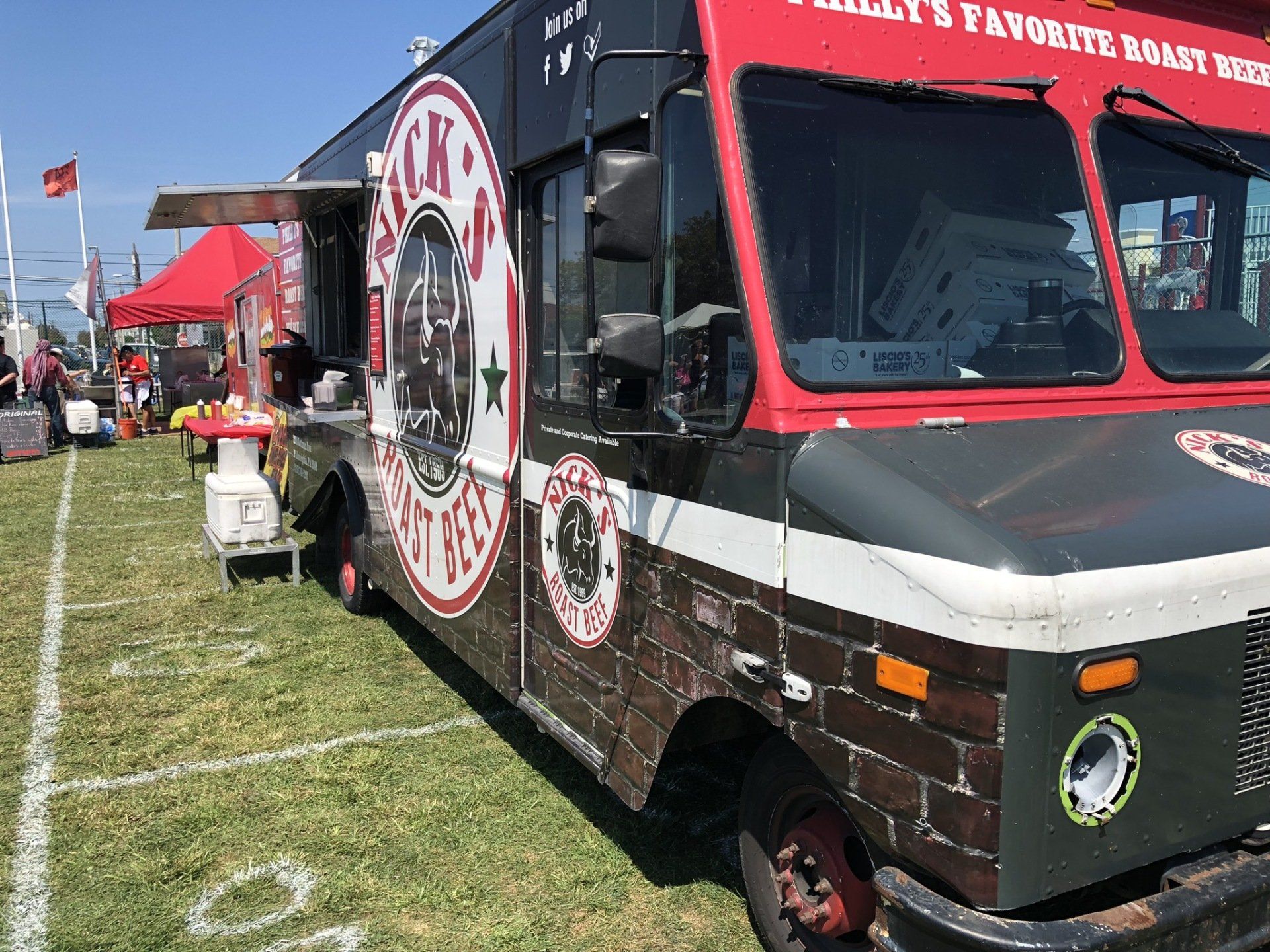 A food truck is parked in a grassy field.