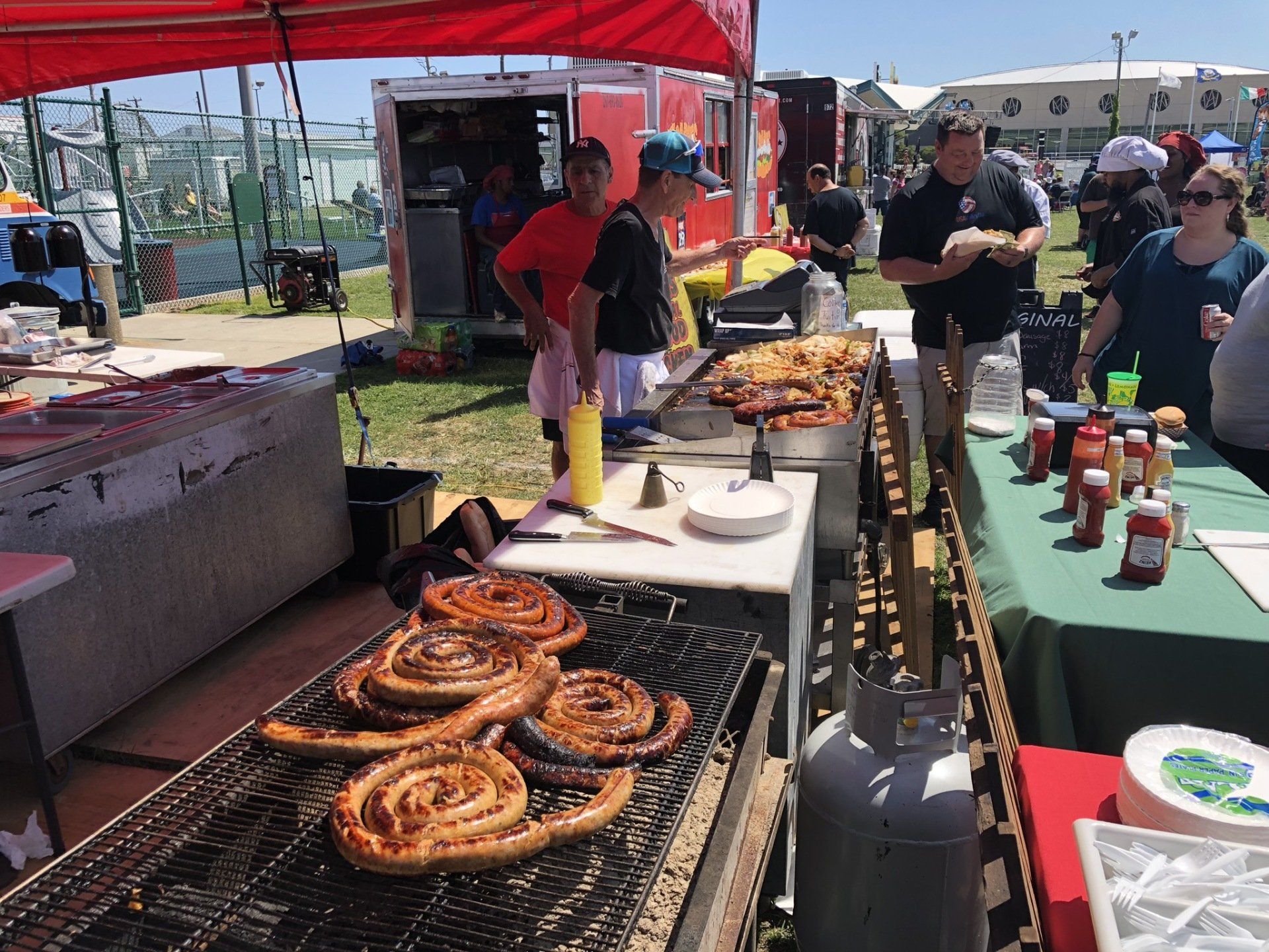 A group of people are standing around a grill cooking food.
