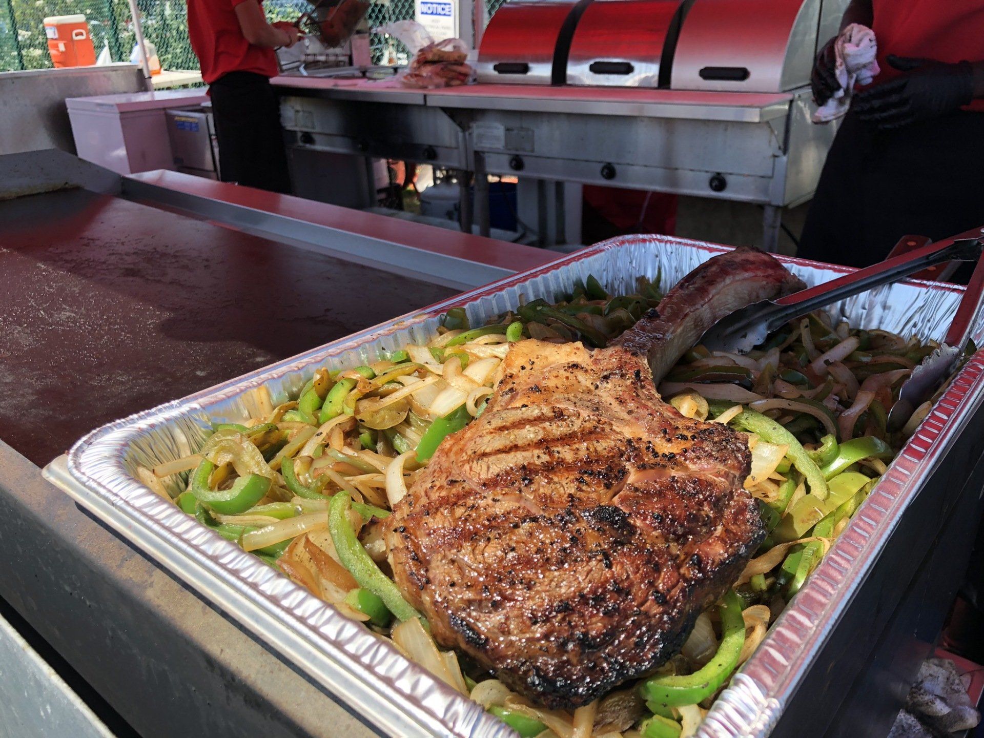 A large steak is sitting on top of a tray of vegetables.