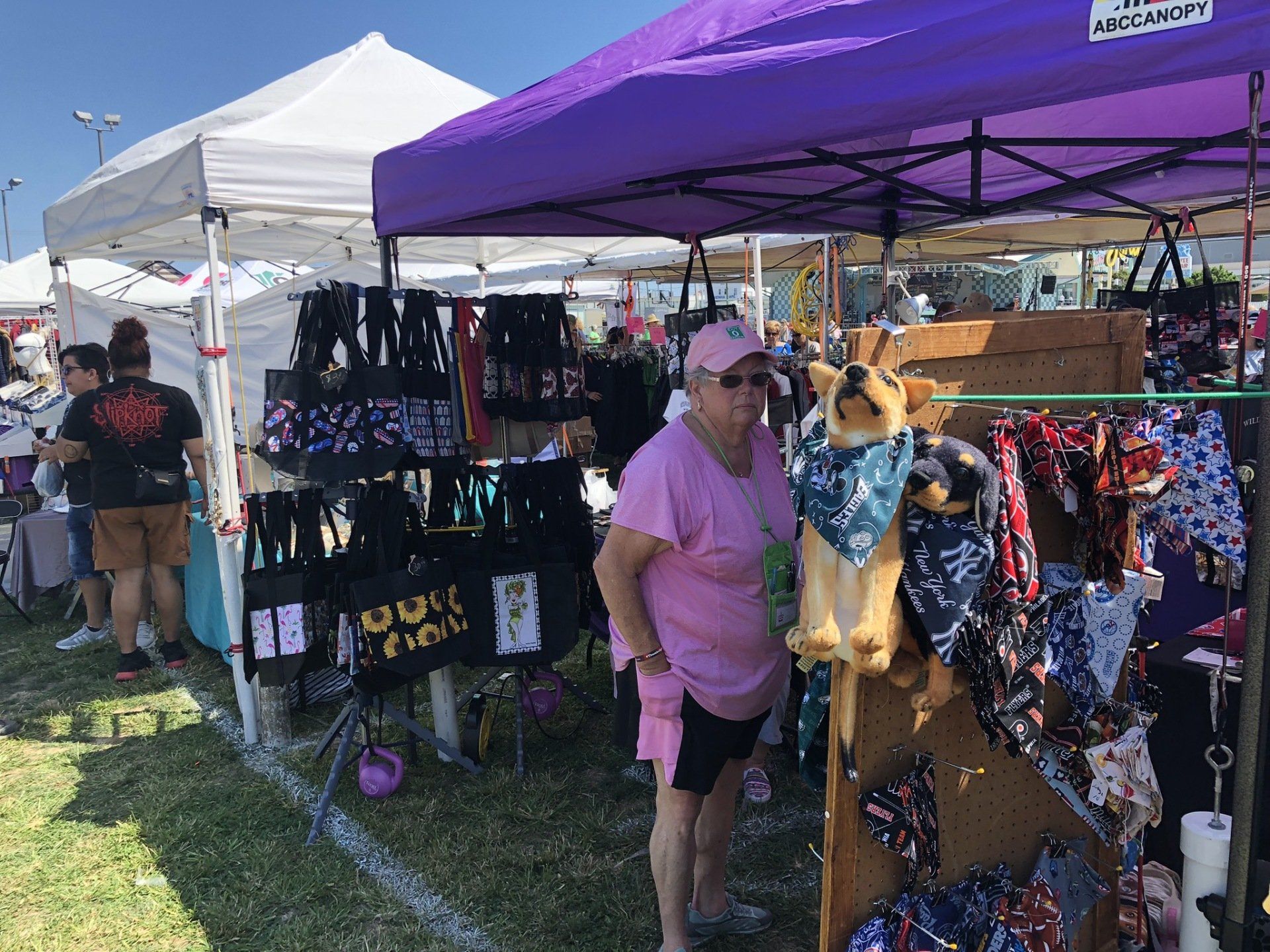 A woman in a pink shirt is standing next to a stuffed dog at a market.