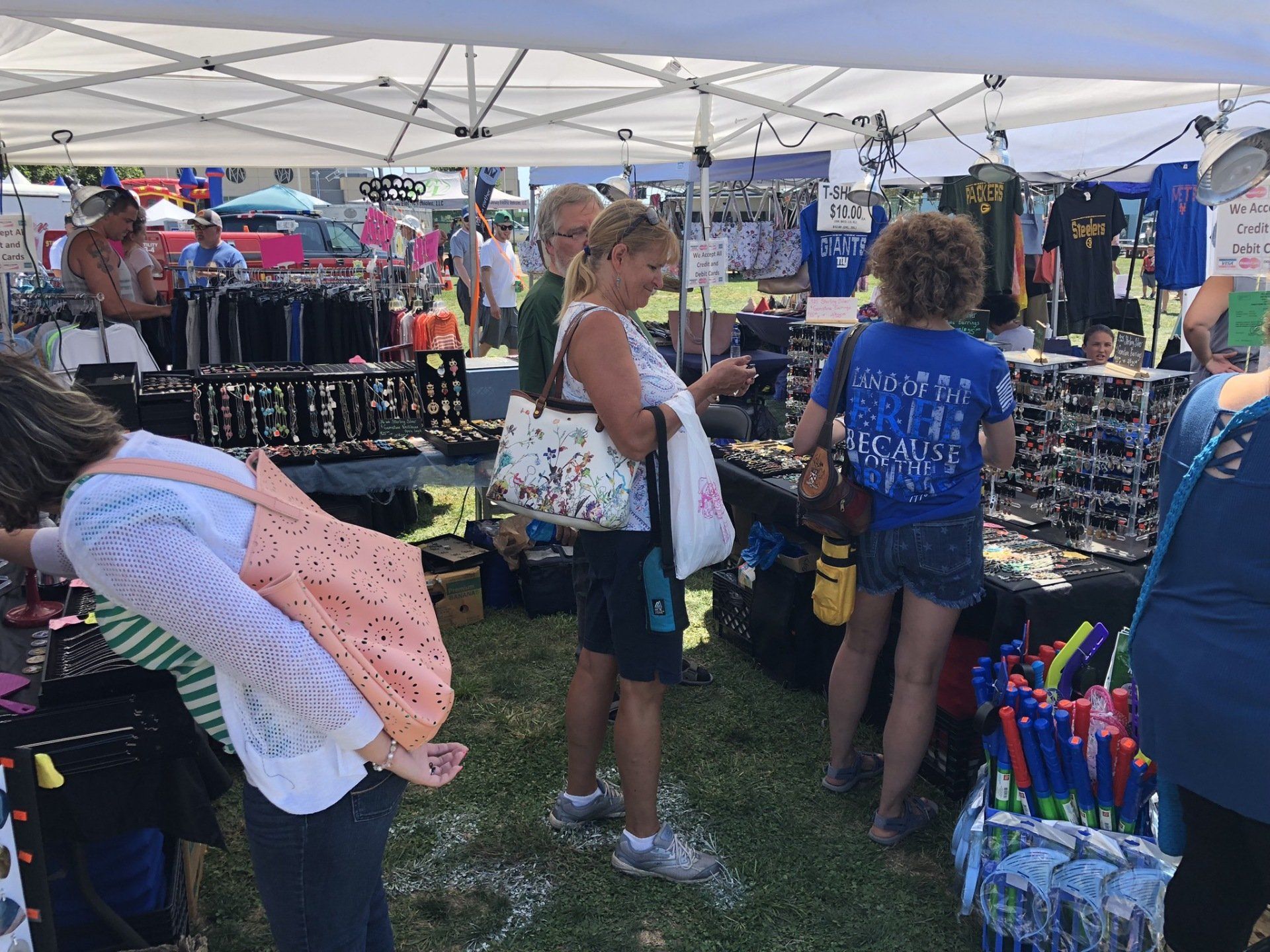 A group of people are standing under a tent at a market.