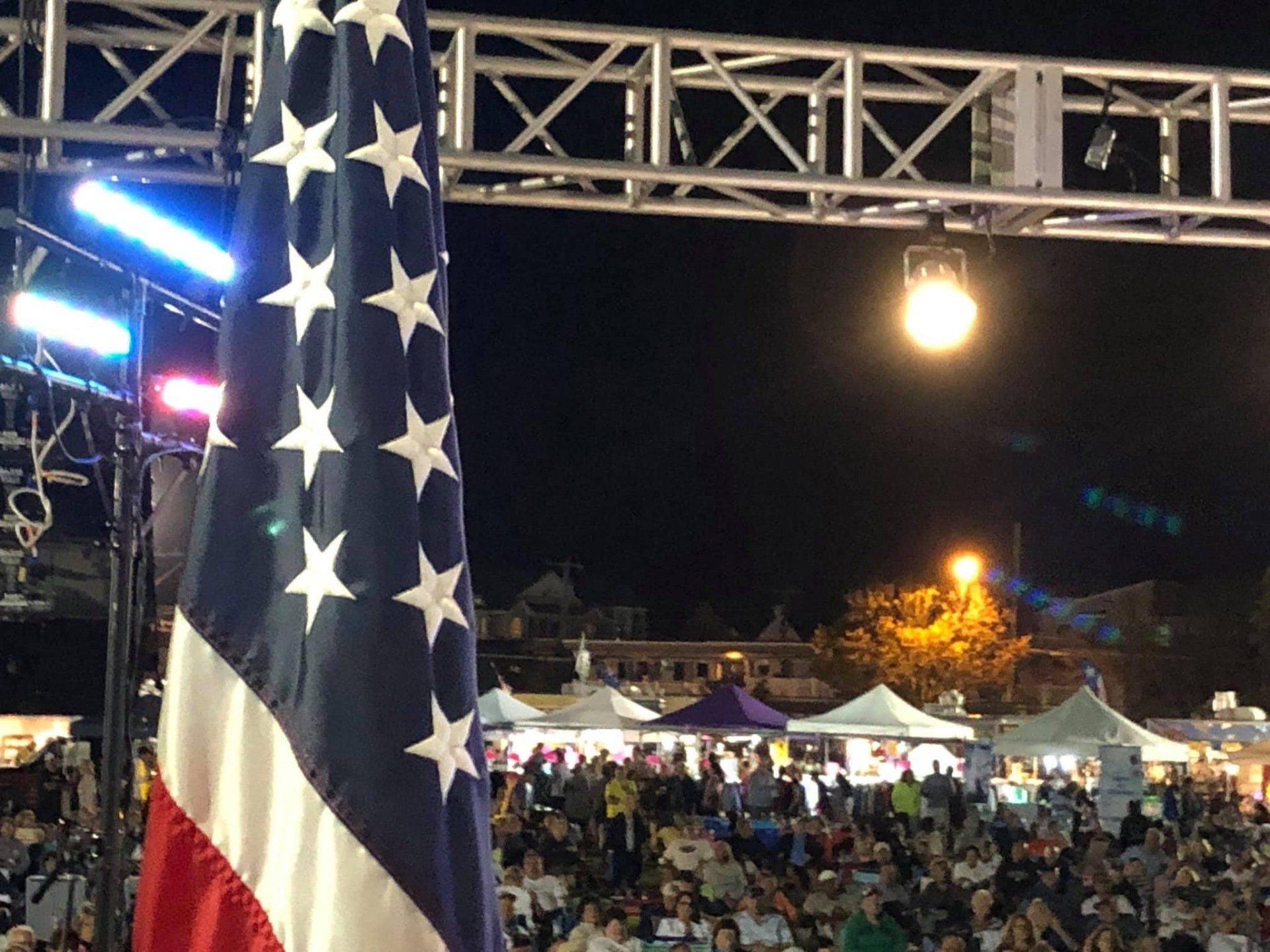 An american flag is flying in front of a crowd at night