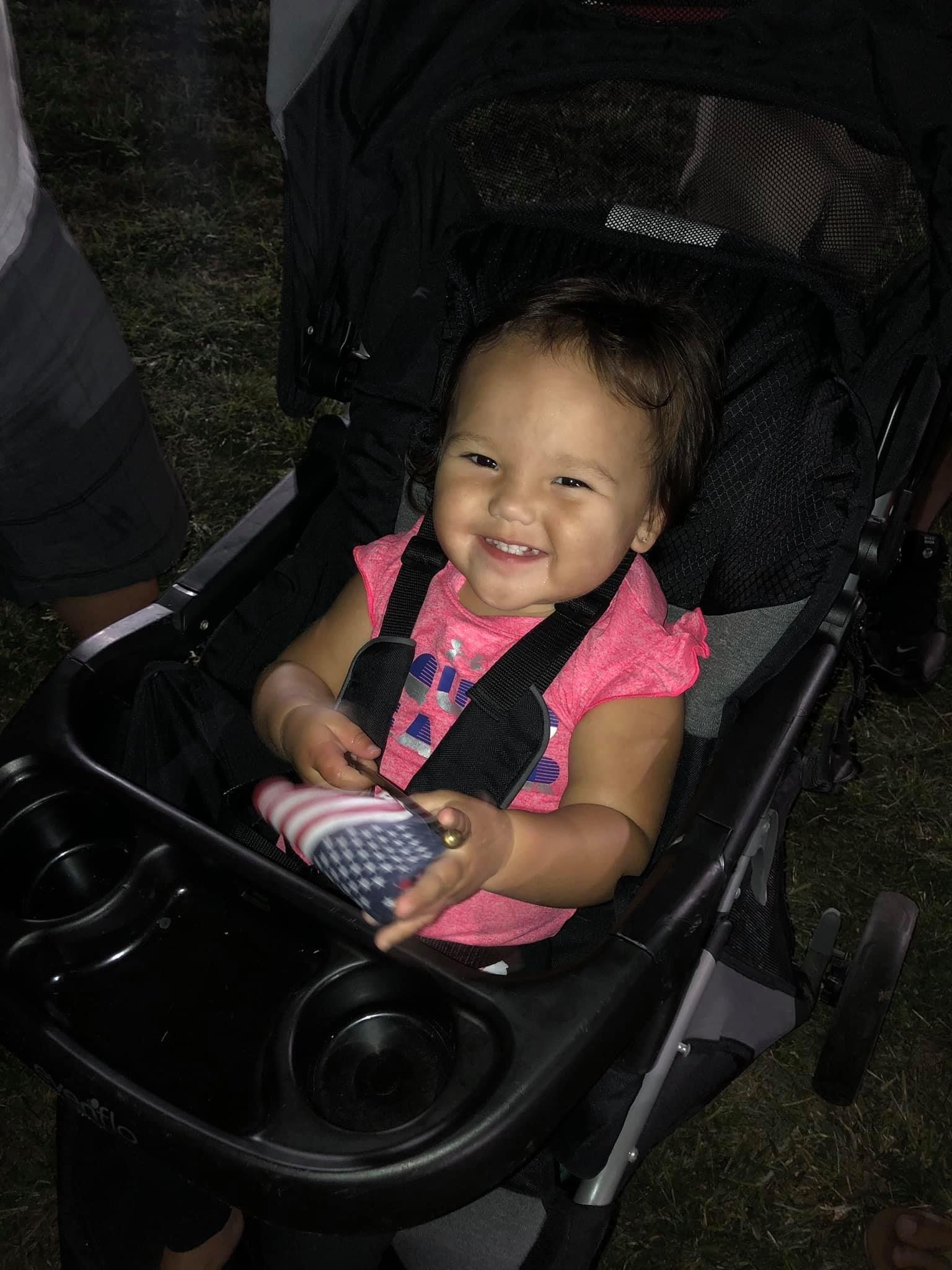 A baby is sitting in a stroller and smiling.