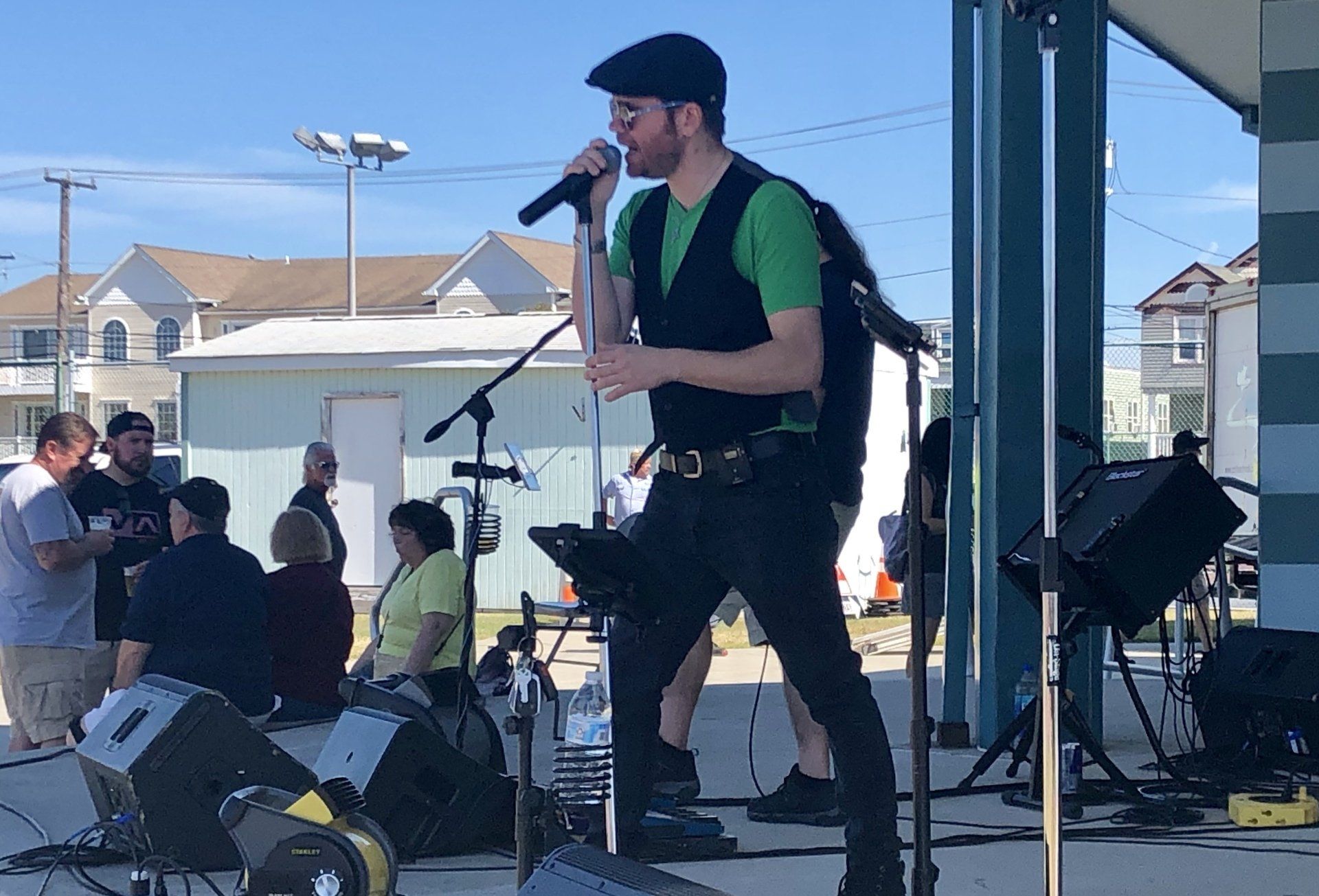 A man in a green shirt is singing into a microphone on a stage.