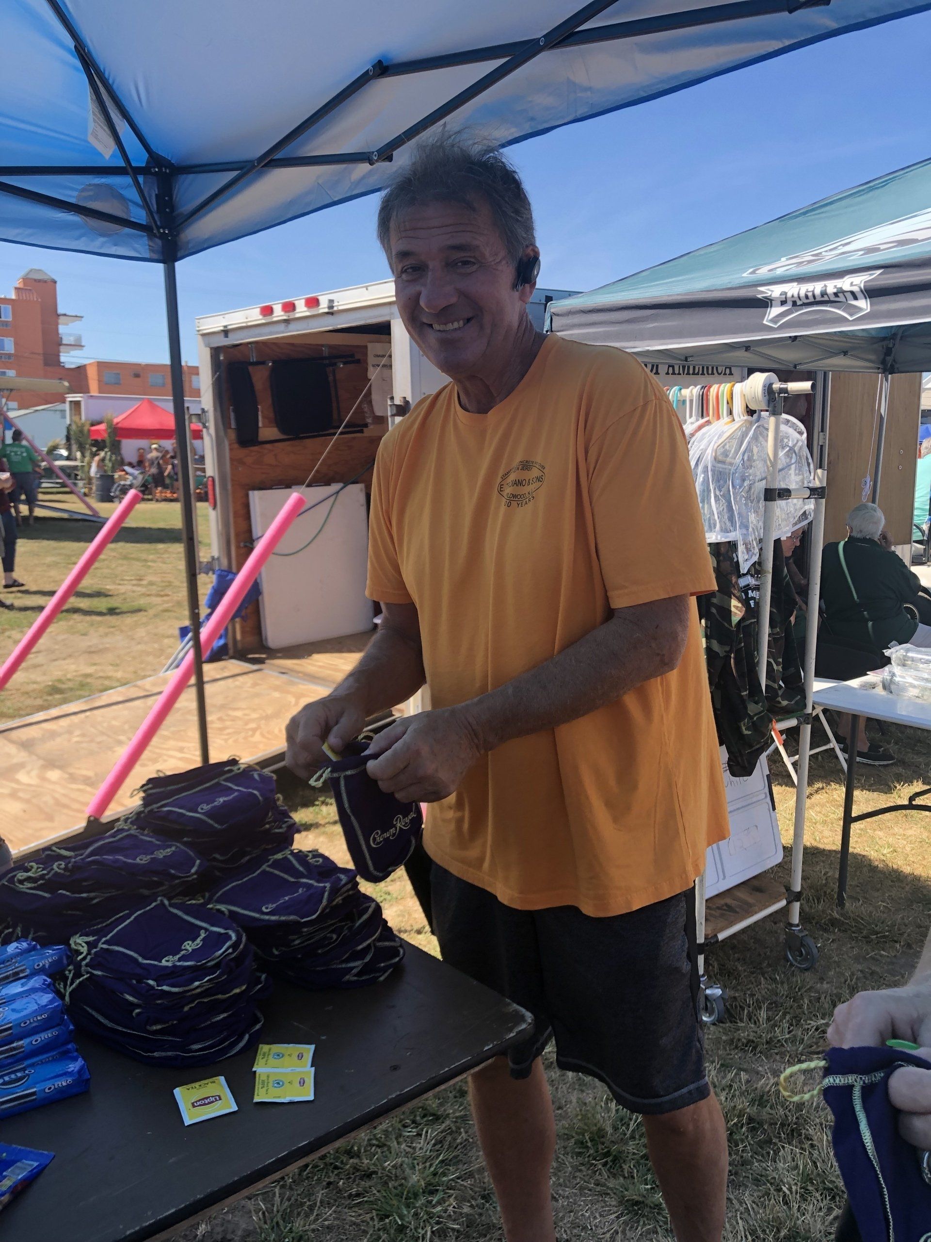 A man in a yellow shirt is standing in front of a table.
