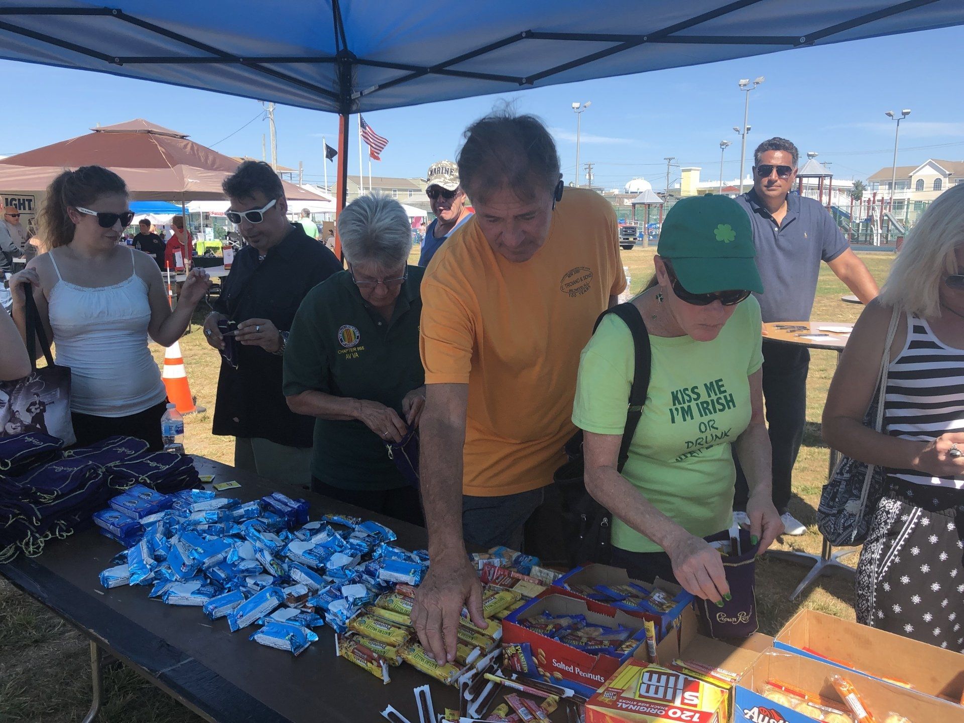 A group of people are standing around a table with candy on it.