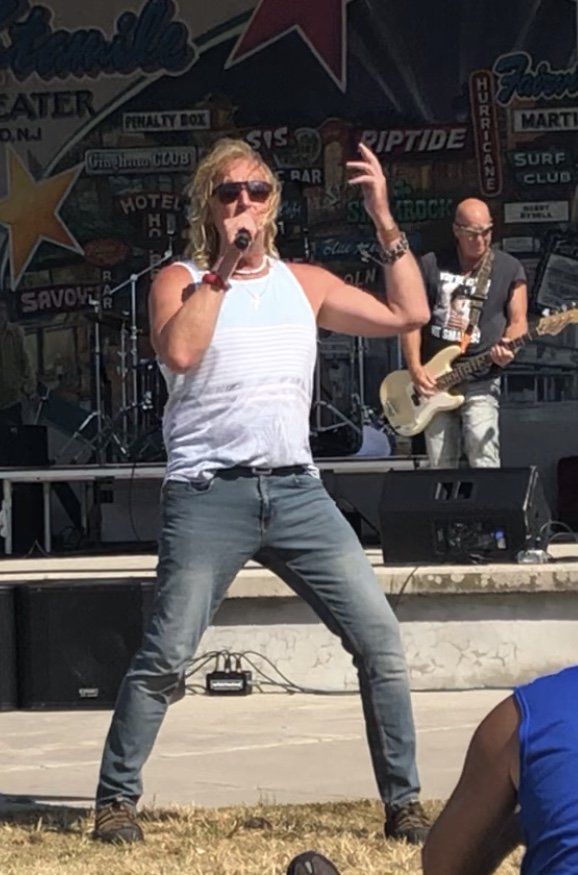 A man is singing into a microphone while standing on a stage.